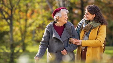 Foto: Seniorin und Schwiegertochter spazieren Arm in Arm im Park