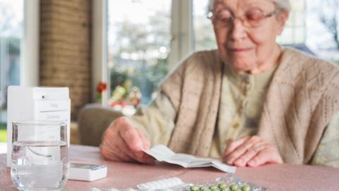 Bild einer alten Dame am Tisch mit Medikamenten
